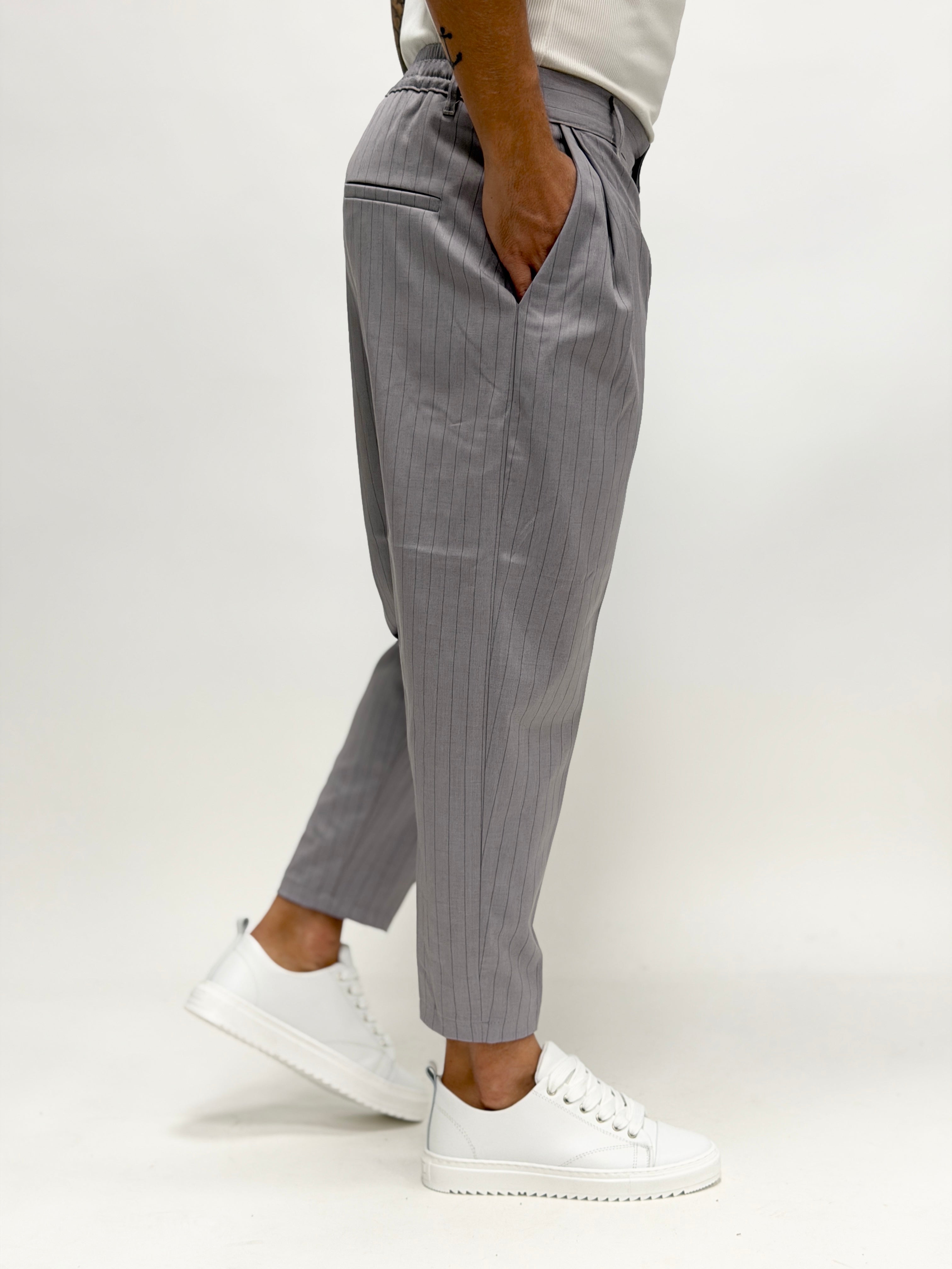 Pantalón gris claro con pinzas de la marca AUTUNNO/INVERNO 26 para hombre, mostrando el diseño de rayas.